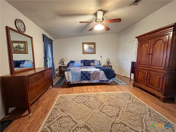 a spacious bedroom with a bed and wooden floor