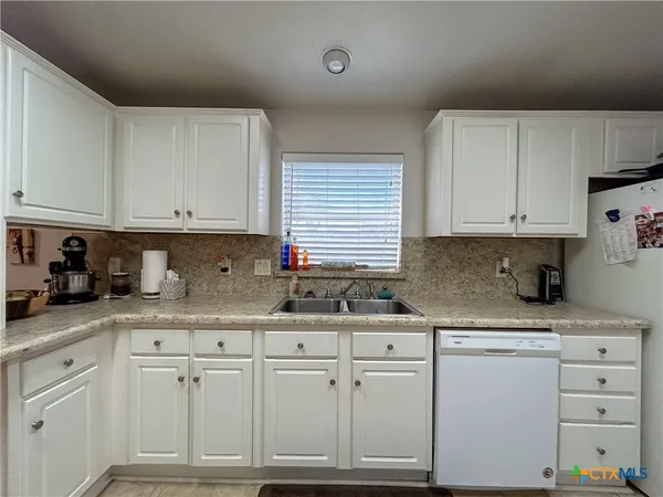 a kitchen with granite countertop white cabinets and white appliances