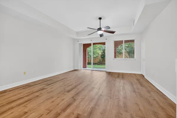 an empty room with wooden floor chandelier and windows