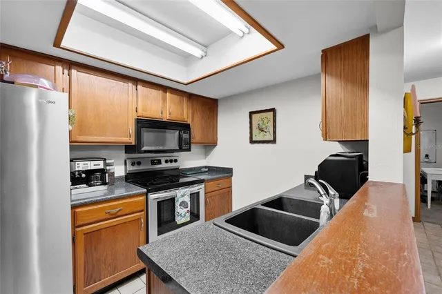 a kitchen with stainless steel appliances granite countertop a stove top oven a sink a dining table and chairs with wooden floor