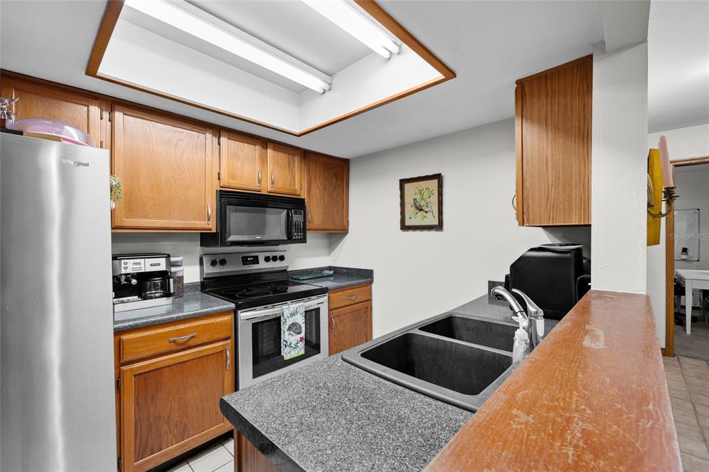 900 Southwest 62nd Boulevard, Unit L79 Gainesville, FL 32607 - Photo 16 of 24 a kitchen with stainless steel appliances granite countertop a stove top oven a sink a dining table and chairs with wooden floor