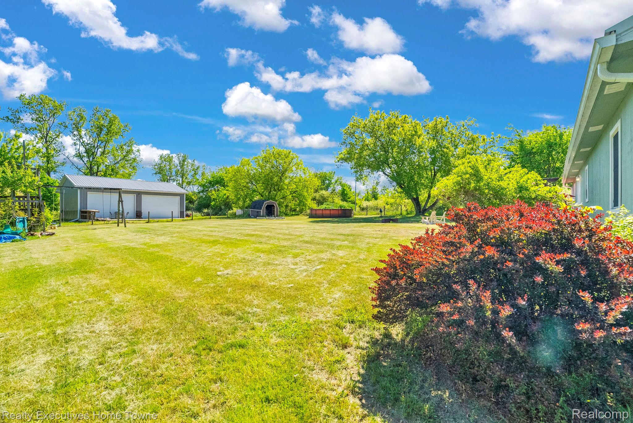 6560 Roach Road Lexington, MI 48450 - Photo 26 of 36 Expansive green lawn with mature trees and a detached garage featuring multiple bays