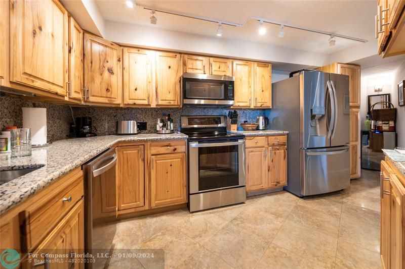a kitchen with stainless steel appliances granite countertop a stove a sink dishwasher a refrigerator and a microwave