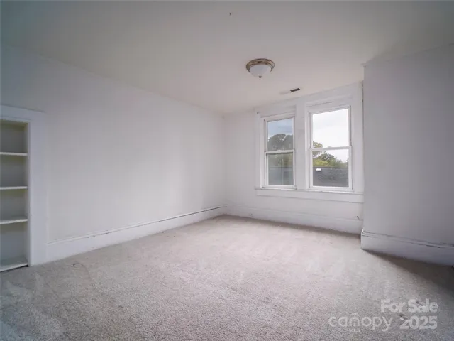 an empty room with windows and refrigerator