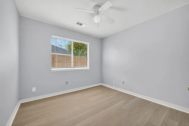 an empty room with wooden floor and fan