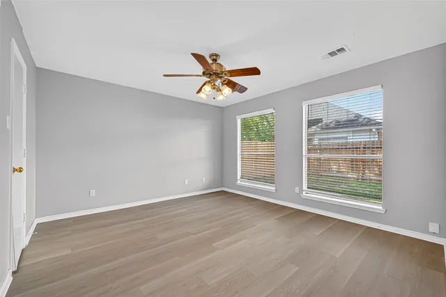 a view of an empty room with a window and wooden floor