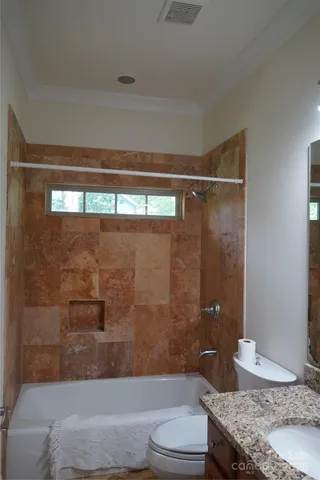 a bathroom with a granite countertop bathtub shower sink vanity and toilet
