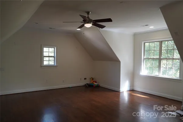 an empty room with wooden floor fan and windows