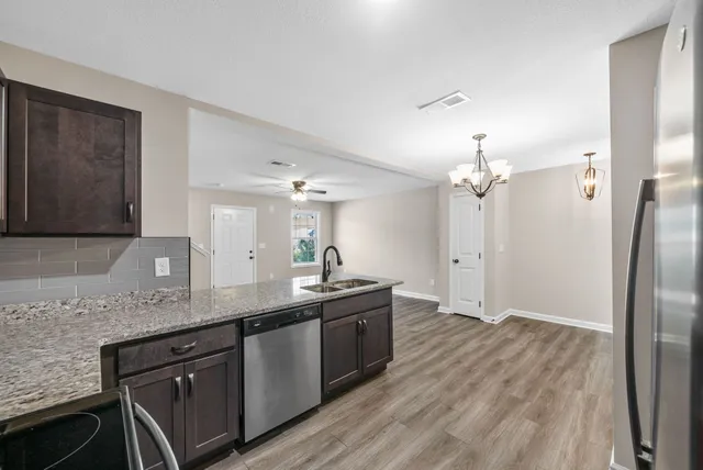 a kitchen with granite countertop a sink cabinets and stainless steel appliances