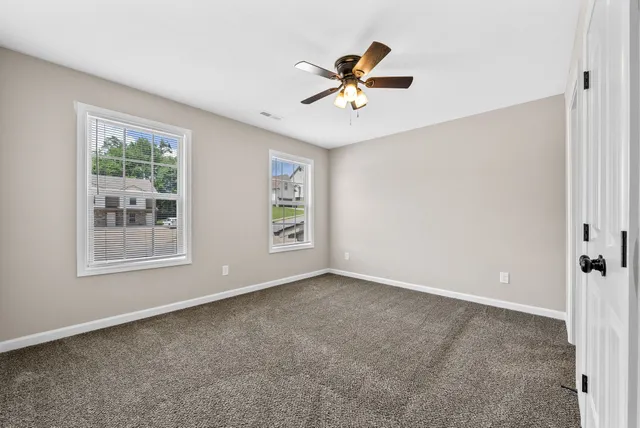 a view of a livingroom with a ceiling fan & windows