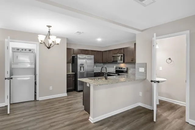 a kitchen with stainless steel appliances granite countertop a refrigerator a stove a sink and white cabinets with wooden floor