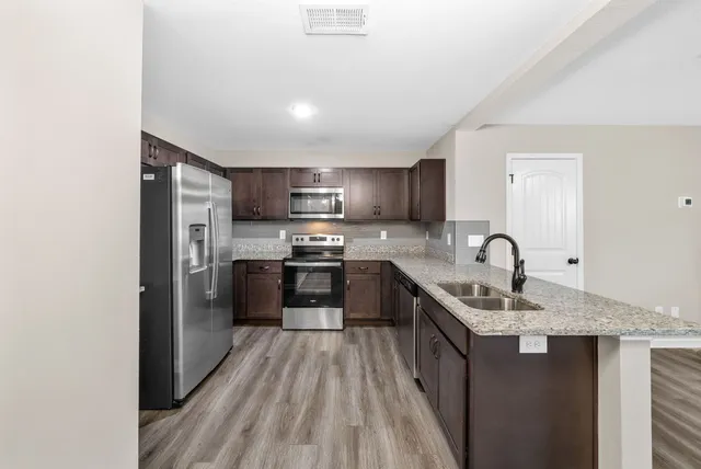 a kitchen with stainless steel appliances granite countertop a sink stove refrigerator and cabinets
