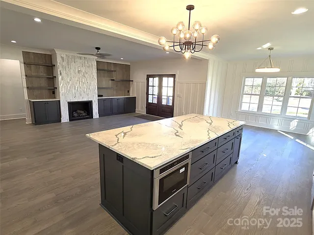 a room with kitchen island a chandelier and wooden floor