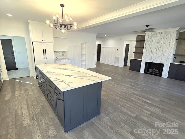 a large kitchen with kitchen island a sink dishwasher a refrigerator and wooden floor