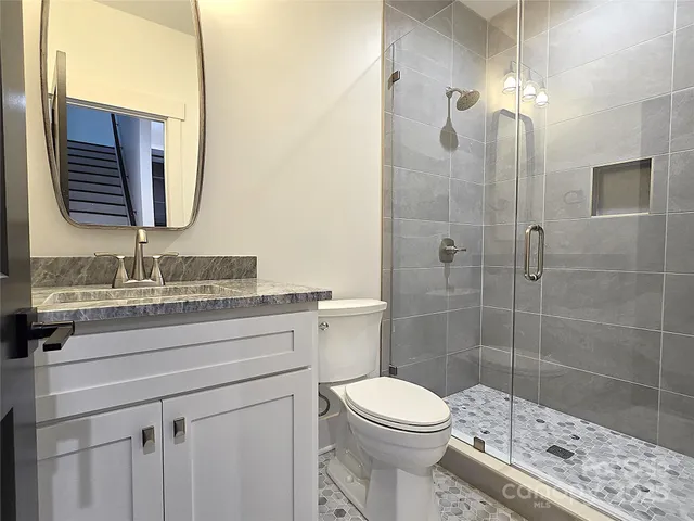a bathroom with a granite countertop sink toilet a mirror and shower