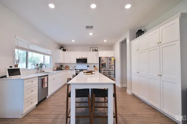 a large kitchen with kitchen island a sink white cabinets and stainless steel appliances