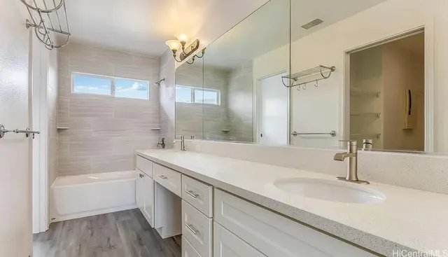 a bathroom with a sink double vanity granite tub shower and a mirror