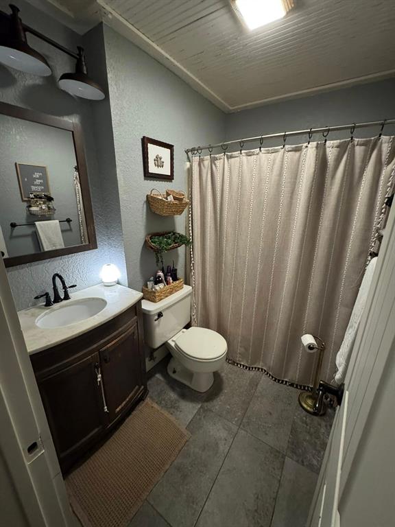 806 Oak Hollow Road Eastland, TX 76448 - Photo 18 of 18 Full bath featuring a textured wall, vanity, and curtained shower