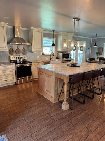 a kitchen with kitchen island granite countertop a sink cabinets and wooden floor