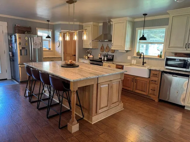 a kitchen with stainless steel appliances granite countertop a table chairs refrigerator and sink