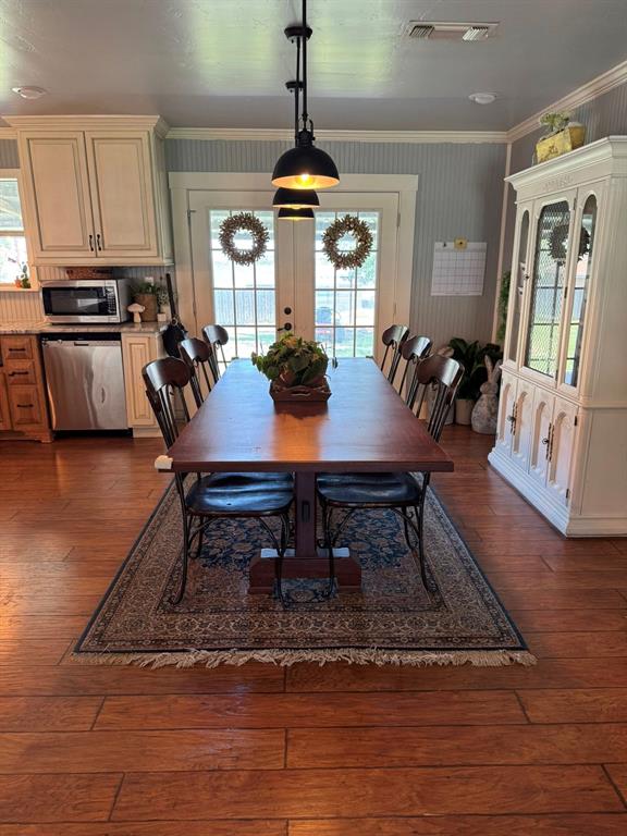 806 Oak Hollow Road Eastland, TX 76448 - Photo 5 of 18 Dining area with healthy amount of natural light, dark wood-type flooring, crown molding, french doors, and wallpapered walls