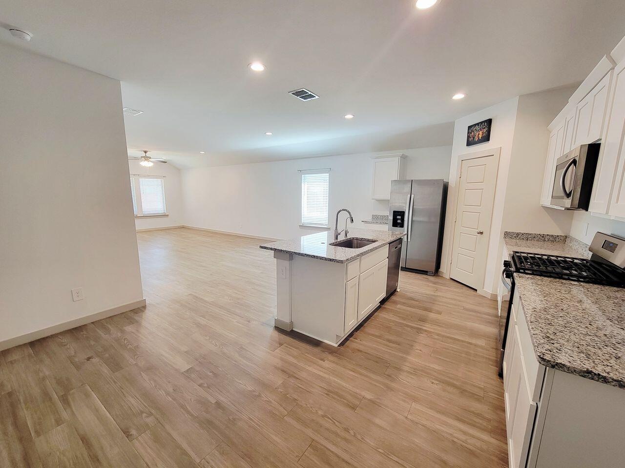 7324 9th Street Lubbock, TX 79416 - Photo 2 of 21 a large room with stainless steel appliances kitchen island granite countertop wooden floors and a sink