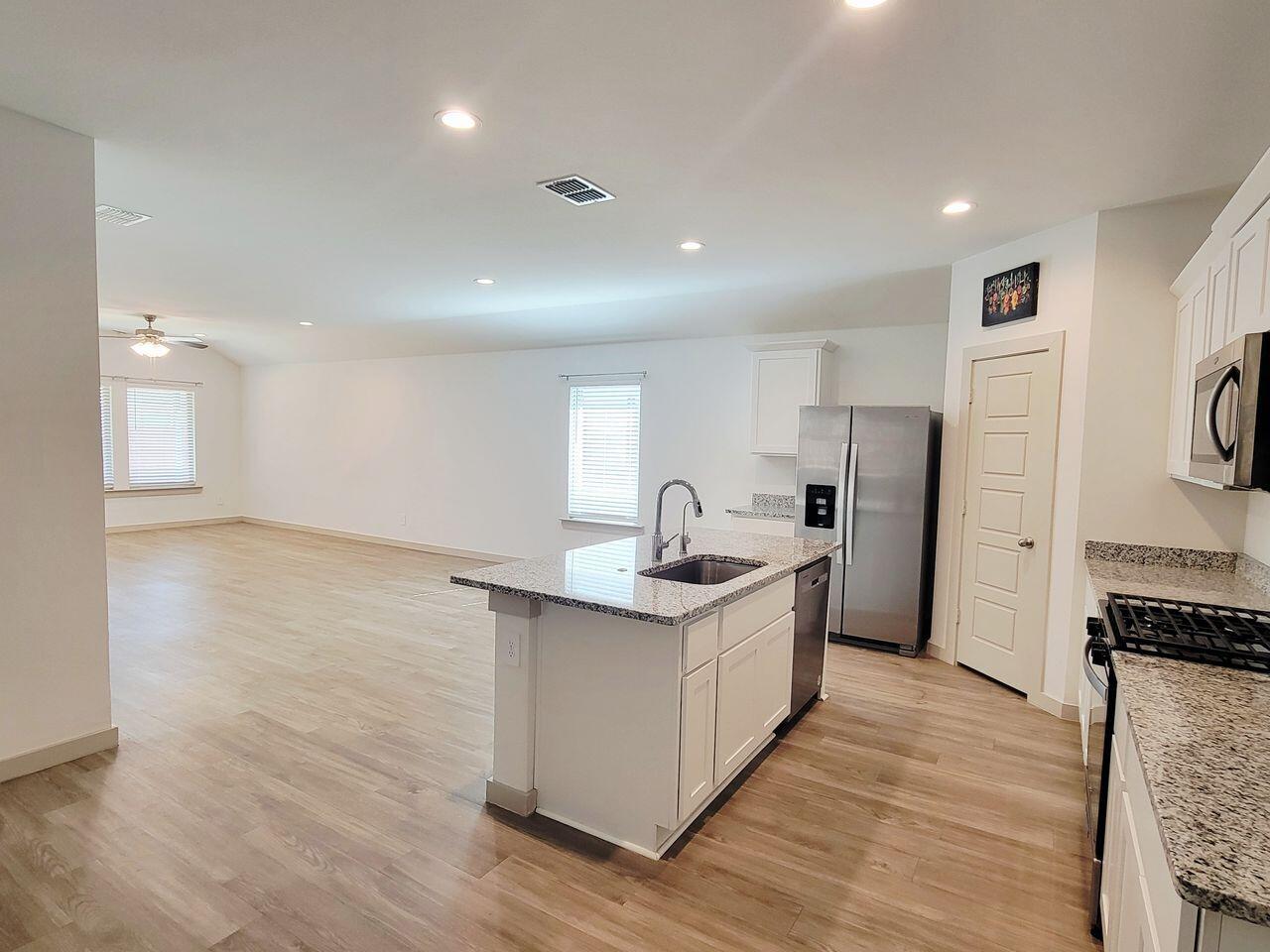 7324 9th Street Lubbock, TX 79416 - Photo 3 of 21 a kitchen with stainless steel appliances granite countertop a sink stove and refrigerator