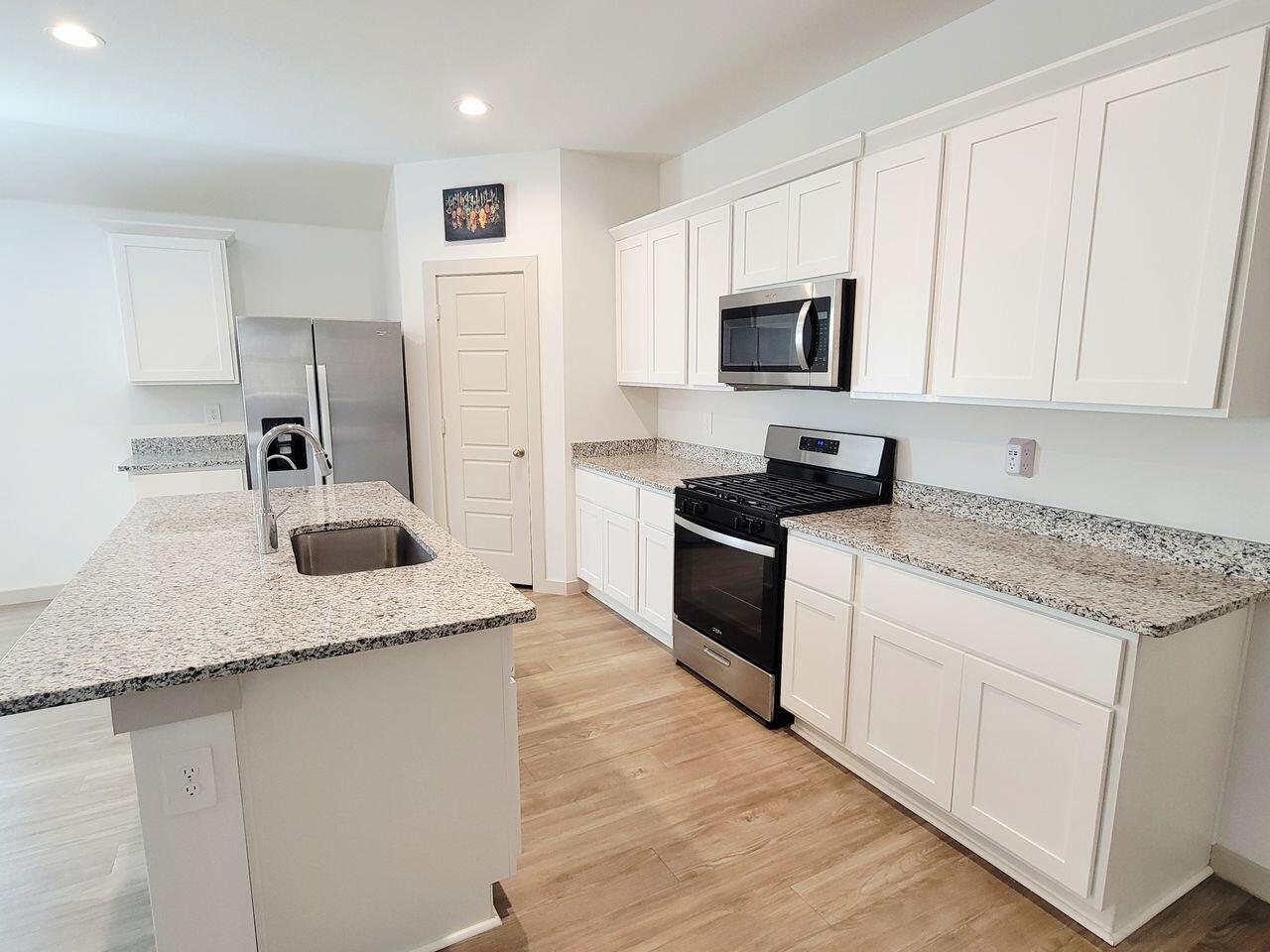 7324 9th Street Lubbock, TX 79416 - Photo 4 of 21 a kitchen with granite countertop a sink and white cabinets