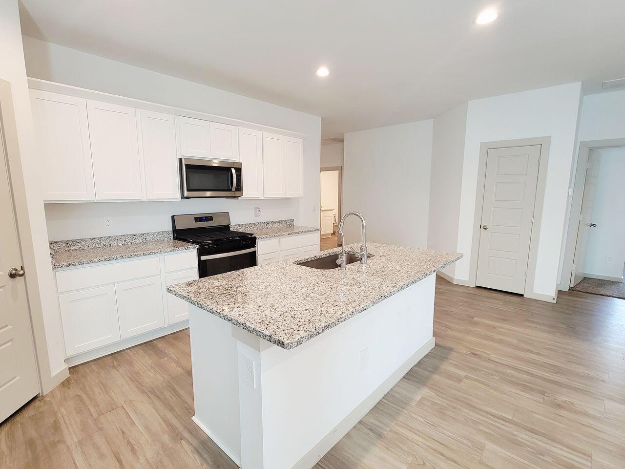 7324 9th Street Lubbock, TX 79416 - Photo 7 of 21 a kitchen with granite countertop a sink and a stove top oven