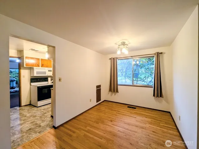 a view of an empty room with a window and wooden floor