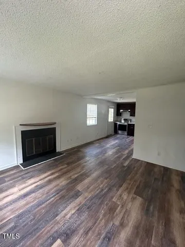 a view of empty room with a fireplace and wooden floor