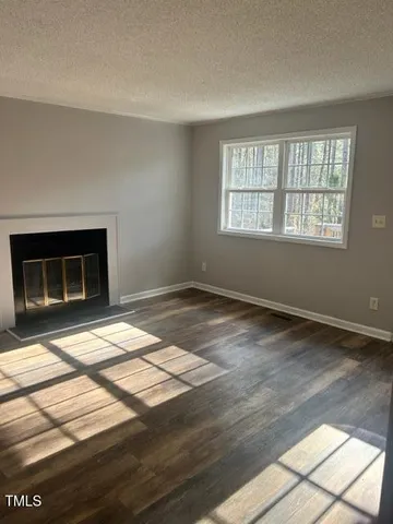 a view of empty room with wooden floor and fireplace