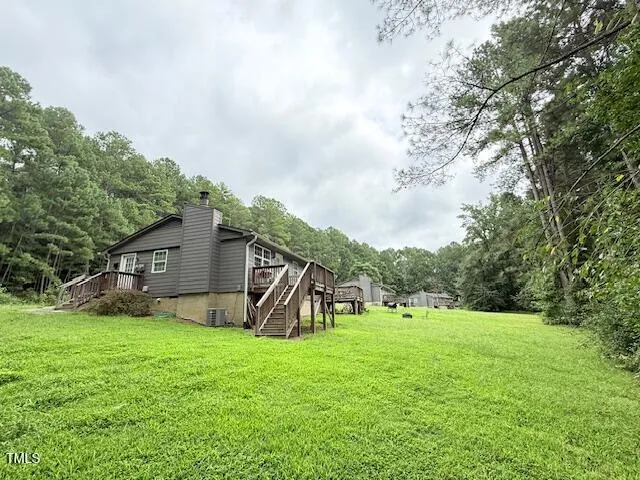 a view of a house with a big yard and potted plants and large trees