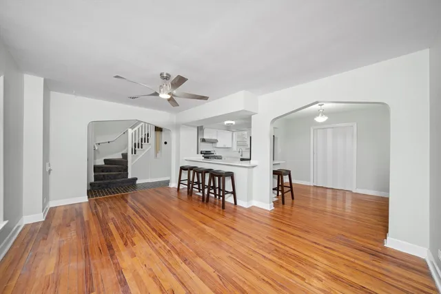 a view of a livingroom with furniture wooden floor front door and a ceiling fan