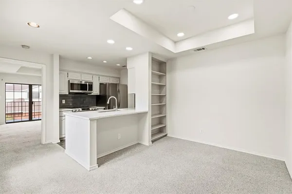 a kitchen with stainless steel appliances a refrigerator oven a sink dishwasher with a dining table and chairs