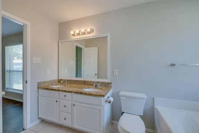 a bathroom with a granite countertop toilet a sink and a mirror