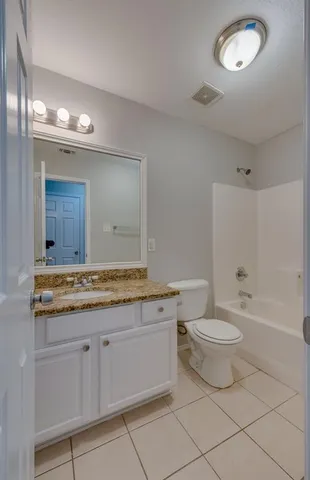 a bathroom with a granite countertop sink a toilet mirror and bathtub