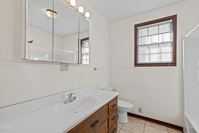 a bathroom with a granite countertop sink a toilet and a mirror
