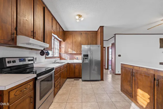 a kitchen with stainless steel appliances granite countertop a refrigerator a stove and a sink