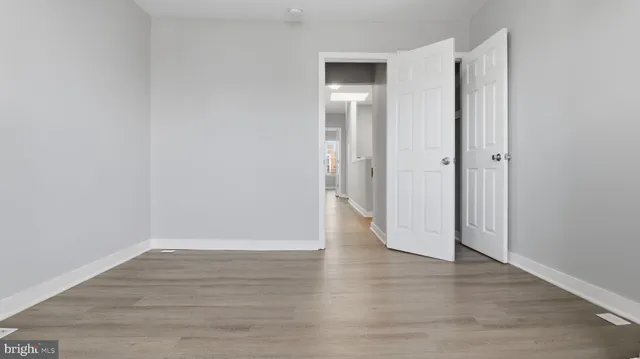 a view of an empty room with wooden floor and closet