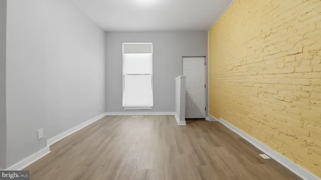 a view of a hallway with wooden floor and a bathroom
