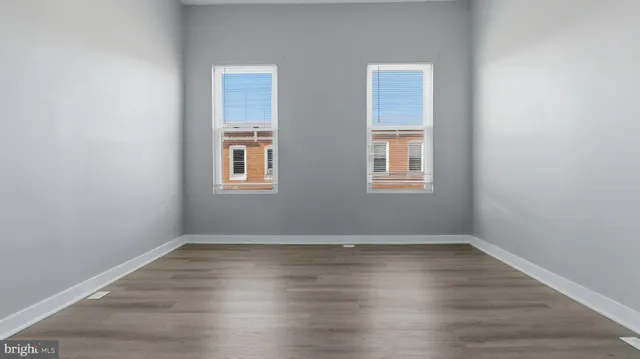 an empty room with wooden floor and windows