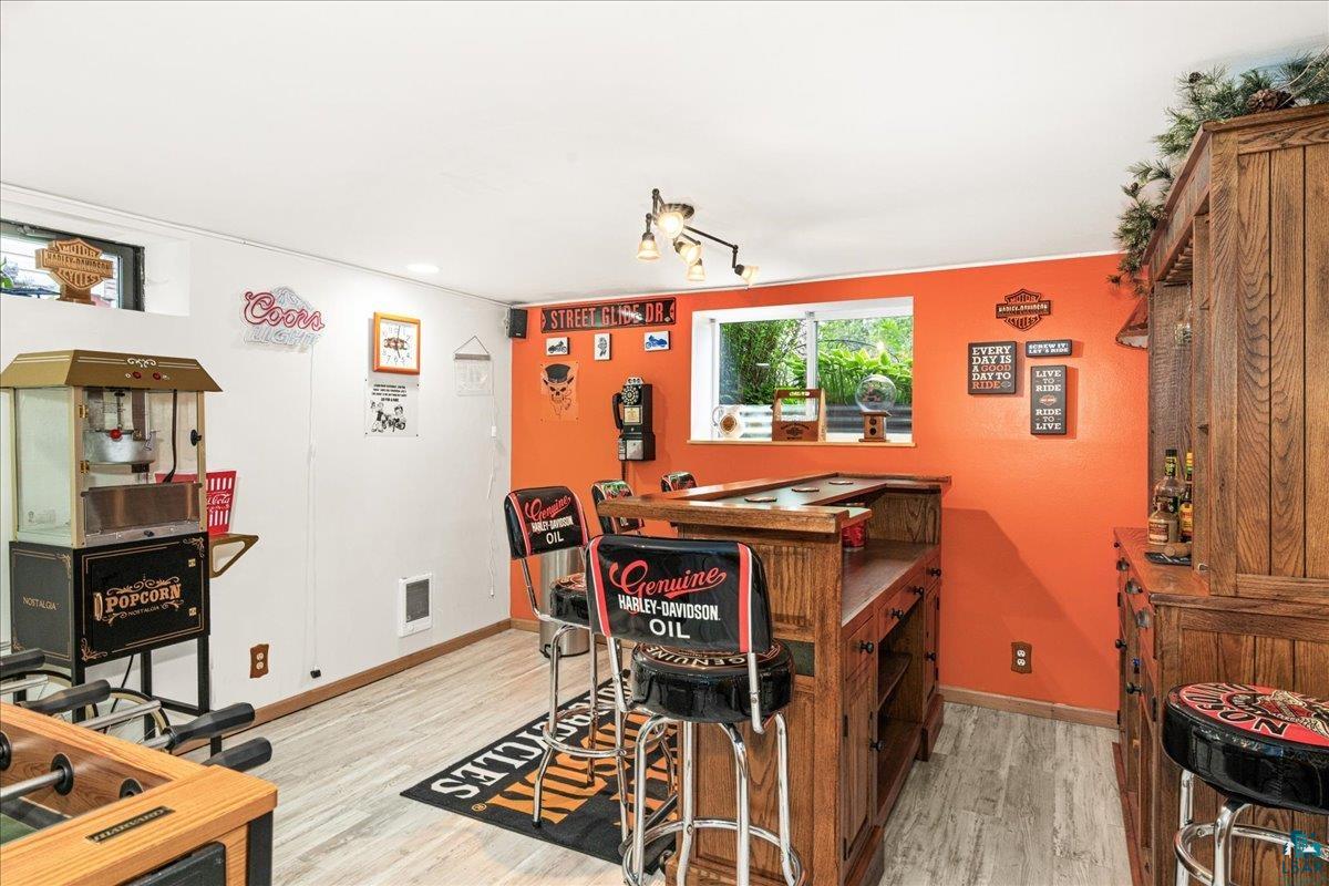 130 West Austin Street Duluth, MN 55803 - Photo 17 of 35 Entertainment space featuring a built-in wooden bar with seating, wood-finish flooring, a window offering natural light, and track lighting