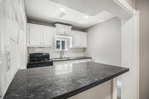 a kitchen with kitchen island granite countertop a sink cabinets and stainless steel appliances