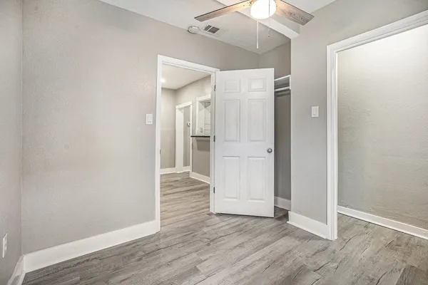 an empty room with wooden floor and a ceiling fan