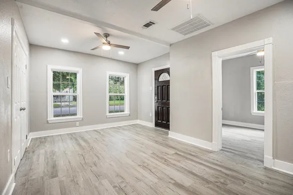 a view of an empty room with wooden floor and a window