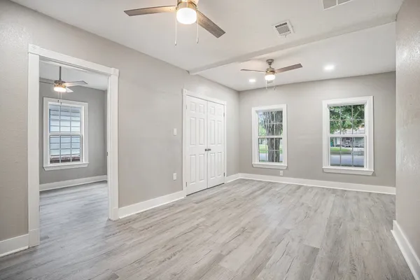 a view of an empty room with wooden floor and a window