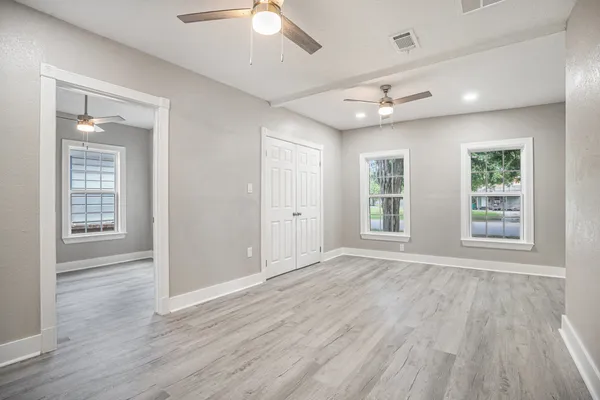 a view of an empty room with wooden floor and a window