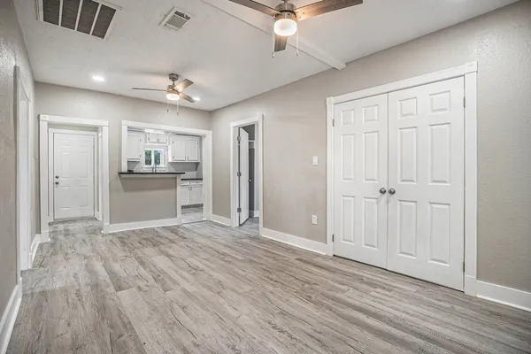 an empty room with wooden floor kitchen view and a window