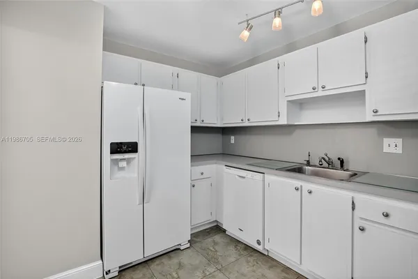 a kitchen with granite countertop white cabinets and refrigerator